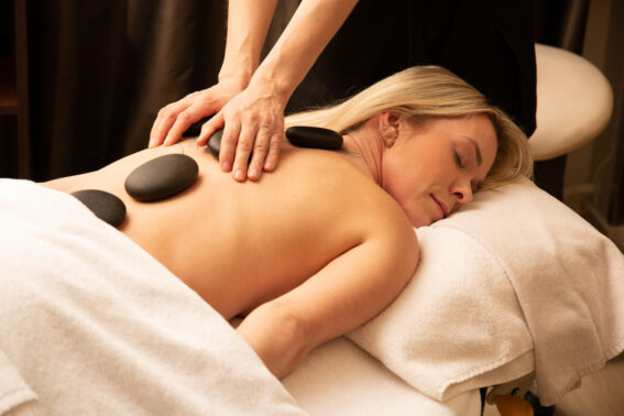 Asiakas nauttii Hot Stone Oil -kuumakivihieronnasta lämpimien kivien ja öljyhieronnan yhdistelmästä